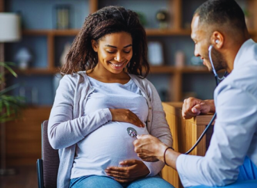Pregnant African American woman consulting with her gynecologist for a routine check-up, discussing the management and risks of anaemia in pregnancy.