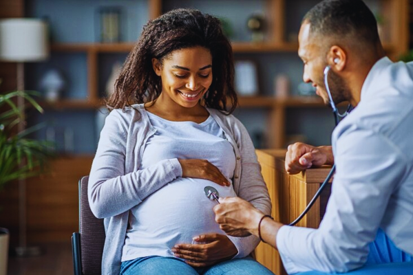 Pregnant African American woman consulting with her gynecologist for a routine check-up, discussing the management and risks of anaemia in pregnancy.