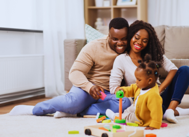 Joyful couple playing with their daughter at home, embracing parenthood after exploring effective infertility solutions.