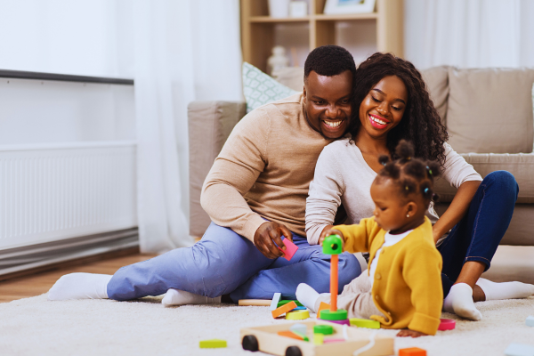 Joyful couple playing with their daughter at home, embracing parenthood after exploring effective infertility solutions.