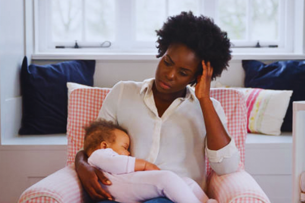 Exhausted new mother experiencing mother sleep deprivation, gently holding her sleeping baby daughter in a nursery at home, showing signs of postnatal depression