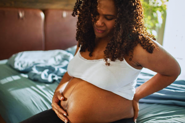 Pregnant woman experiencing early morning abdominal pain, a possible symptom of placenta abruption requiring immediate medical attention