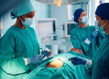 Black surgeon leading her medical team while performing a C-section procedure in a hospital operating room
